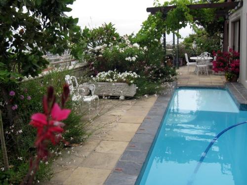 una piscina en un jardín con flores y una mesa en 123 Ocean View Drive Apartment, en Ciudad del Cabo