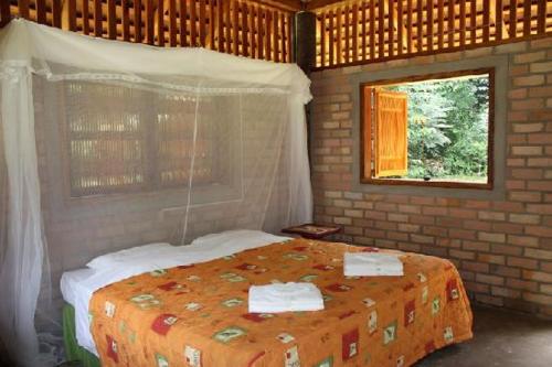 ein Schlafzimmer mit einem Bett in einer Ziegelwand in der Unterkunft ATTA Rainforest Lodge in Surumatra