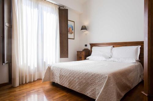 a bedroom with a bed with white sheets and a window at Hotel La Piazzetta in Castellammare del Golfo