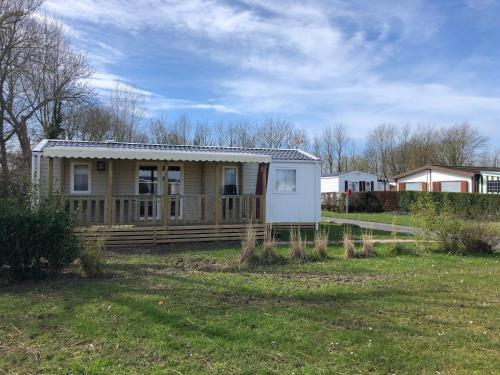 a small house with a porch on a yard at Camping la Haie Penée **** in Saint-Quentin-en-Tourmont