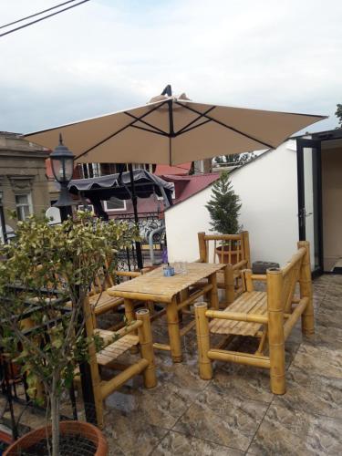 una mesa de madera y sillas con sombrilla en Guest House Nice, en Tiflis