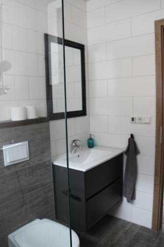 a bathroom with a toilet, sink, mirror and bath tub at South Iceland Guesthouse in Steinar