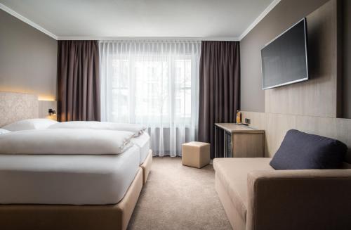 AWA Hotel في ميونخ: غرفة فندقية بسريرين واريكة