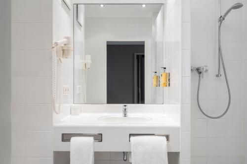 a bathroom with a shower, sink, and mirror at AWA Hotel in Munich