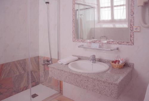 y baño con lavabo, espejo y ducha. en Victoria, en Trujillo
