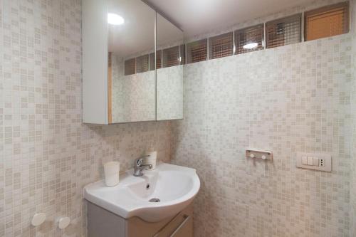a white bathroom with a sink and a mirror at Olina Apartments in Naples
