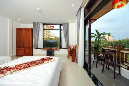 a bedroom with a bed and a balcony with a television at Threeway Riverside Villa in Hoi An