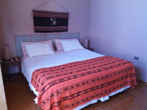 a bedroom with a large bed with a colorful blanket at Hostal Casa Turipite in San Pedro de Atacama