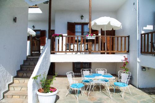 a patio with chairs and a table and an umbrella at F & B Summer Collection - Holiday Flats in Sozopoli