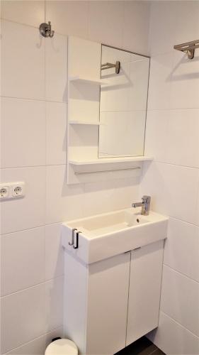 a white bathroom with a sink and a toilet at De Koevoet in Teroele