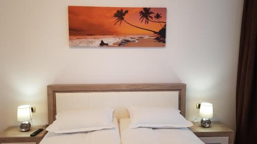 a bedroom with a bed with two lamps and a painting at Eme Apartments 2 in Braşov