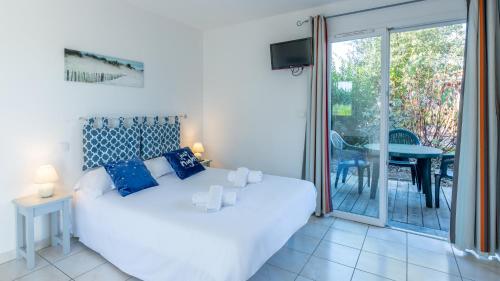 ein Schlafzimmer mit einem weißen Bett und einer Glasschiebetür in der Unterkunft Vacancéole - Le Domaine des Grands Lacs in Parentis-en-Born