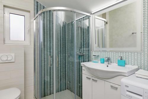 a bathroom with a shower and a sink and a mirror at Bayview Studio Apartment in Tivat