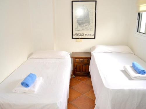 2 Betten in einem Zimmer mit weißer Bettwäsche und blauen Kissen in der Unterkunft Appartement FRONT de MER in Tossa de Mar