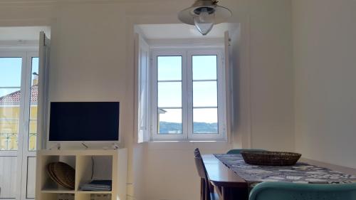 a dining room with a table and two windows at Apartamentos Tejo à Vista in Lisbon