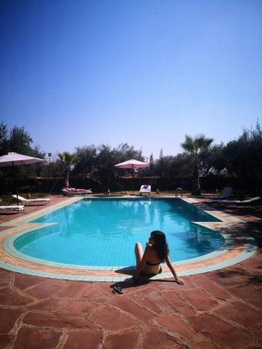 a woman is sitting next to a swimming pool at Riad Sidi Hicham in Marrakech