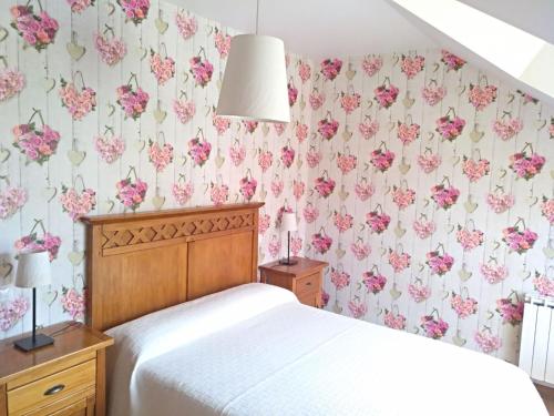 1 dormitorio con cama y papel pintado de flores rosas en Chalet Playa del Sable en Hinojedo