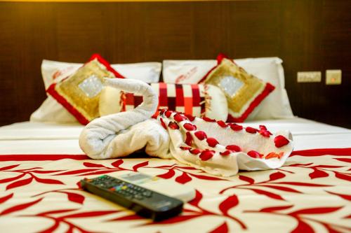 a bed with two towels and a remote control at Hotel Abi's Inn in Thanjāvūr
