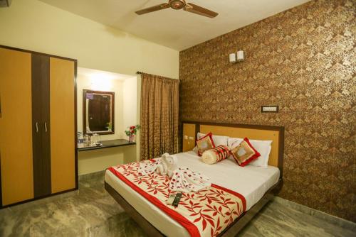 1 dormitorio con 1 cama con manta roja y blanca en Hotel Abi's Inn, en Thanjāvūr