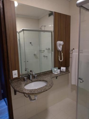 a bathroom with a sink and a glass shower at Premium Vila Velha Ponta Grossa in Ponta Grossa