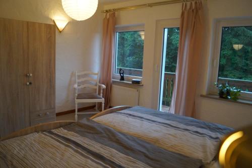 a bedroom with a bed and a chair and windows at Ferienwohnung Shamrock in Hahnenklee-Bockswiese