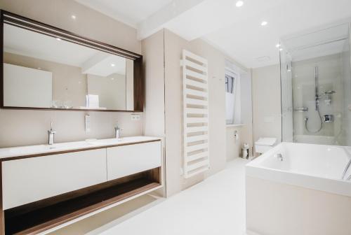 y baño blanco con bañera, lavamanos y ducha. en Karl Suites Palais Wessely, en Viena
