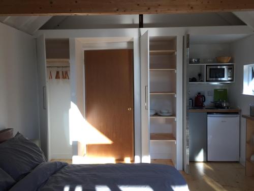 a bedroom with a bed and a door to a kitchen at The Studio @ Aubrey Cottage in Chichester