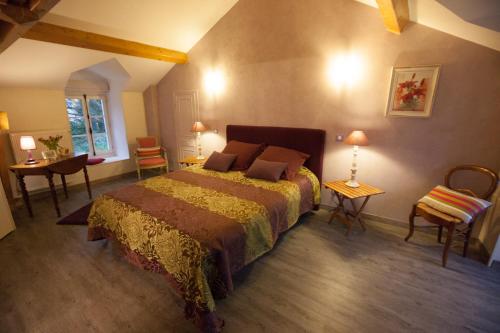 um quarto com uma cama, uma mesa e cadeiras em Manoir d'Orbé em Montreuil-Bellay