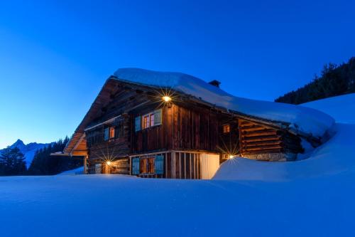 a log cabin in the snow at night at Chalet Berghaus Bartholomäberg in Bartholomäberg