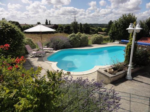 una piscina en un jardín con mesa y sillas en Domaine La Fontaine B&B en Soubran