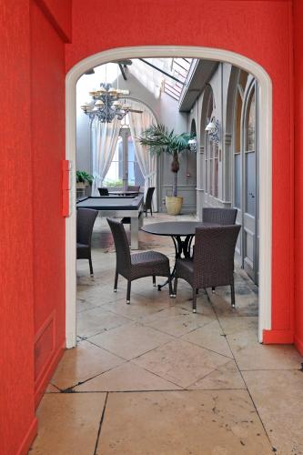 a dining room with tables and chairs and a red wall at LOGIS Hôtel de Bourgogne - Mâcon in Mâcon