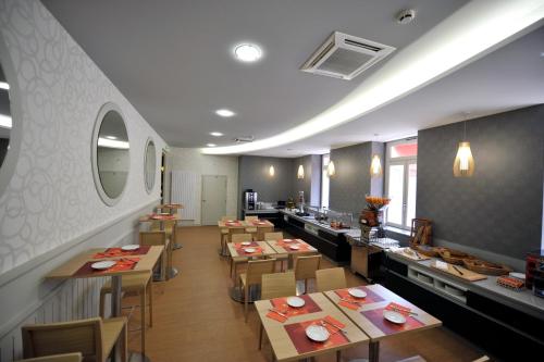 a restaurant with wooden tables and chairs and a counter at LOGIS Hôtel de Bourgogne - Mâcon in Mâcon