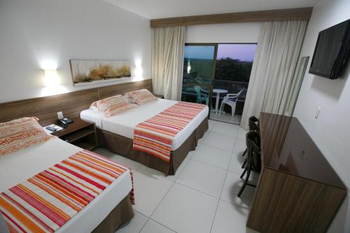 um quarto de hotel com duas camas e uma varanda em Hotel Canarius de Gravatá em Gravatá