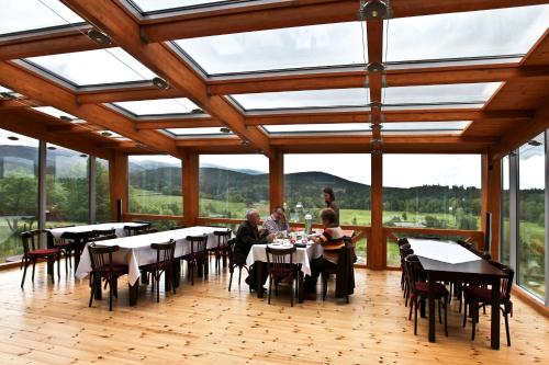 people sitting at tables in a large room with windows at Honor Villa in Izvoare