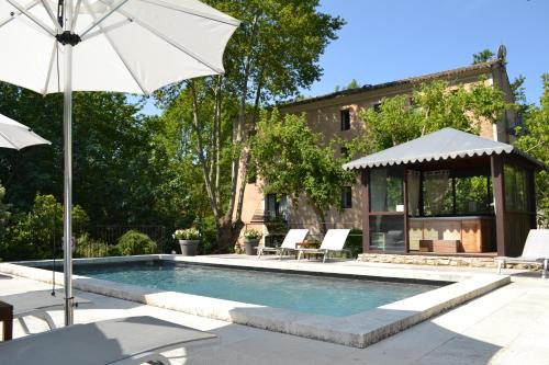 une piscine avec un parasol et des chaises ainsi qu'une maison dans l'établissement Hotel du Poète, à Fontaine-de-Vaucluse