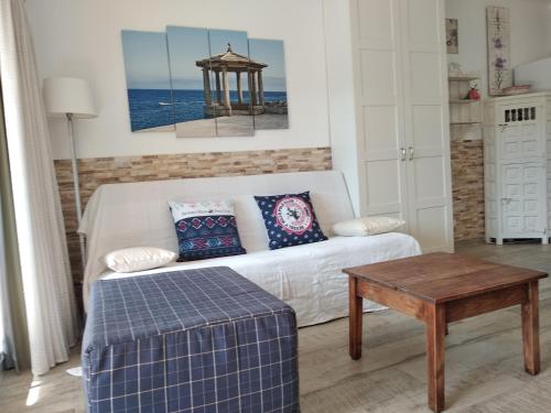 een woonkamer met een witte bank en een tafel bij Sagaro garden, Jardin privado, piscina, 150 m playa in S'Agaro