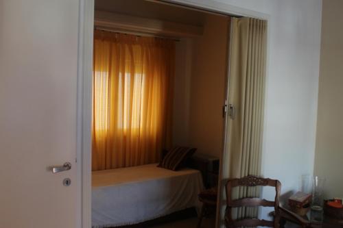 1 dormitorio con 1 cama con cortina naranja y ventana en Departamento en barrio Stella Maris-Zona Playa Varese en Mar del Plata