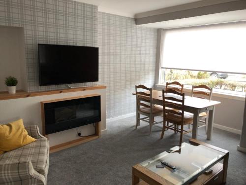 a living room with a television and a table and chairs at Old Police House Causewayhead Stirling in Stirling