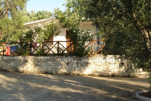 a house behind a stone wall with a fence at Village Valle D'Oro ApartHotel in San Menaio