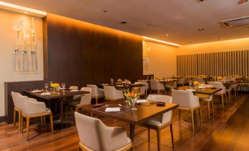 a dining room with tables and white chairs at Hotel Luzeiros São Luis in São Luís