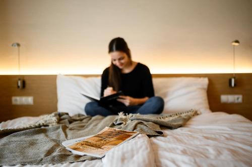 a woman sitting on a bed looking at her phone at Calva B&B Apartments in Malles Venosta