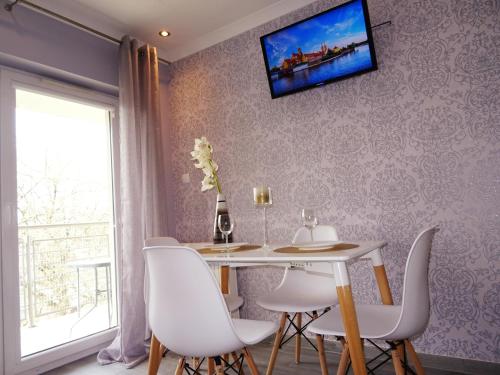 a dining room with a table and chairs and a tv on the wall at Na Grobli in Wrocław