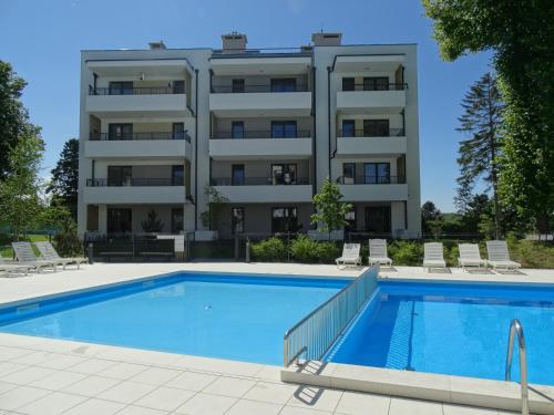 an apartment building with a swimming pool in front of a building at Apartamenty Waterline Ustronie Morskie in Ustronie Morskie