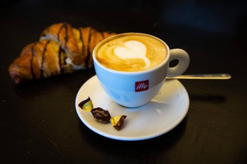 a cup of coffee on a plate with a pastry at Torrione Trento in Trento