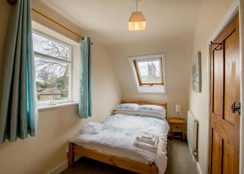 a small bedroom with a bed and two windows at 60 and a half Bailgate in Lincoln