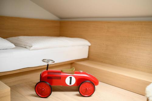 a red toy car in a bedroom with a bed at Calva B&B Apartments in Malles Venosta
