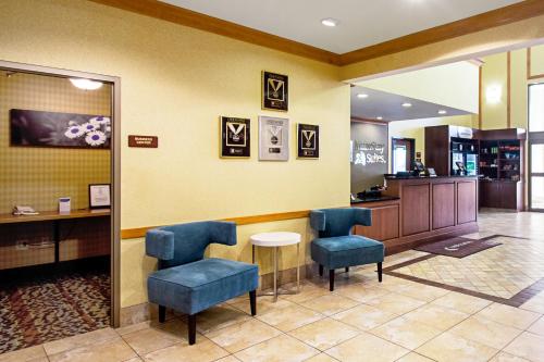 a waiting room with blue chairs and a table at MainStay Suites Madison - Monona in Madison