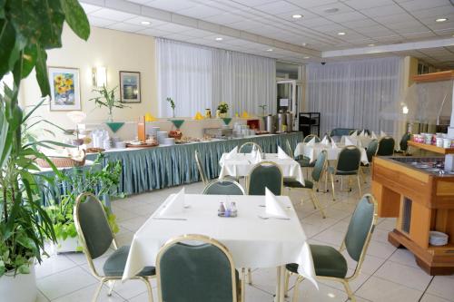 un comedor con mesas blancas y sillas verdes en Hotel Bara Junior en Budapest