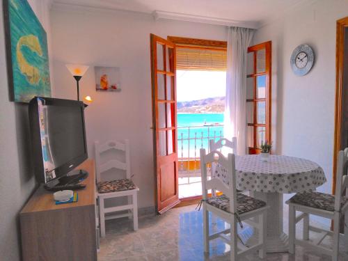 een woonkamer met een tv en een tafel en een balkon bij NEW! BRISA MARINA Apartment, 1a Linea Puerto y Mar in Peñíscola