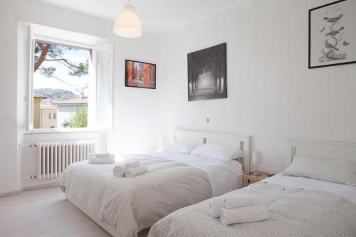 two beds in a white room with a window at Cleo Giglio in Ancona